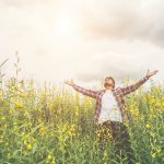 Handsome hipster man standing raising hands in the air in a yell