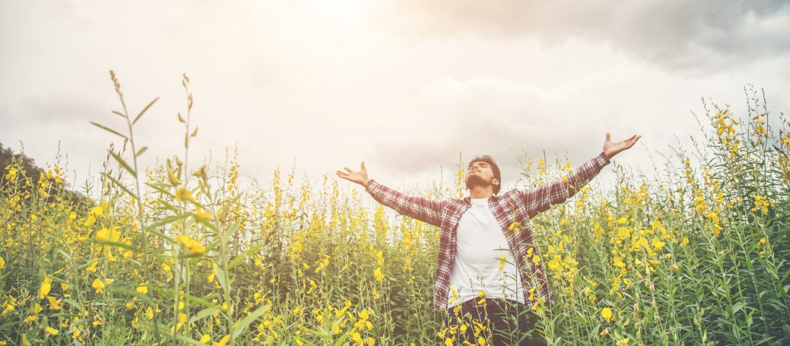 Handsome hipster man standing raising hands in the air in a yell